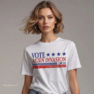 Person wearing a white t-shirt with 'Vote Alien Invasion 2028' text on a plain background
