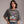 Woman wearing a gray t-shirt with a skeleton and cat graphic and text 'Just Waiting for Halloween'.