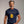 Person wearing a black t-shirt with 'Pardon, Grey Poupon Nostalgic Funny' design on a plain background