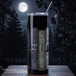 A tall black insulated tumbler with a clear lid and metal straw, featuring gothic book-cover-style graphics including the words 'Wicked Cat' and 'Exorcisms,' set on a wooden surface at night with a full moon and dark trees in the background.