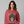 Woman wearing a red sweatshirt with a skull and crossbones design and text.
