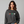 Woman wearing a dark gray sweatshirt with cocktail graphics on a plain background