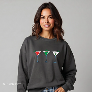 Woman wearing a dark gray sweatshirt with cocktail graphics on a plain background