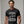 Person wearing a black t-shirt with 'Batman Joker Quote Funny' design on a plain background